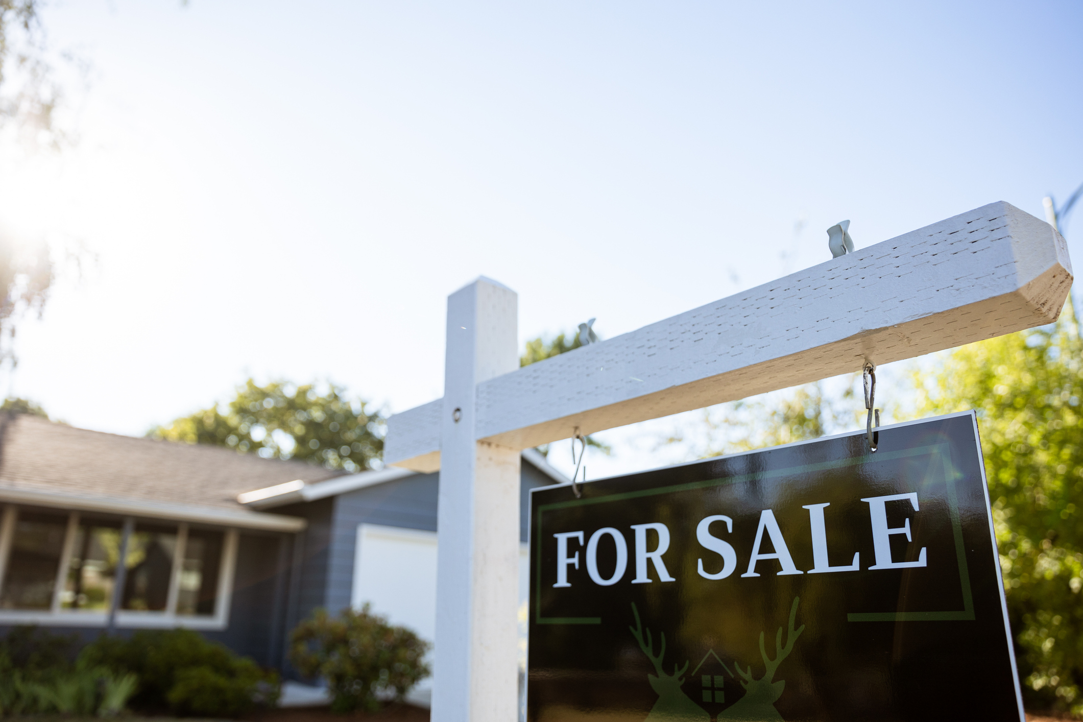 photo of a white picket For Sale sign in front of a suburban home